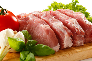 Raw pork on cutting board and vegetables