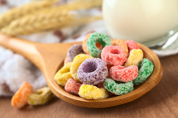 Colorful cereal rings on wooden spoon