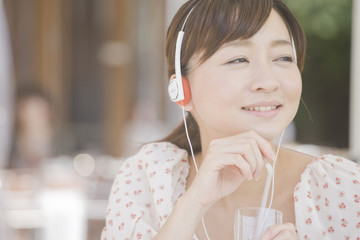 オープンカフェでお茶をしながら音楽を聴く女性