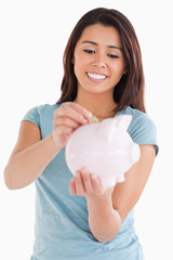 Fototapeta na wymiar Beautiful woman inserting a coin in a piggy bank