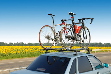 two bicycles mounted on roof of car against sky