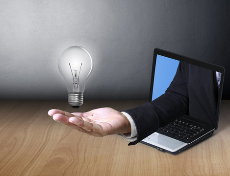 Light bulb in hand and a laptop