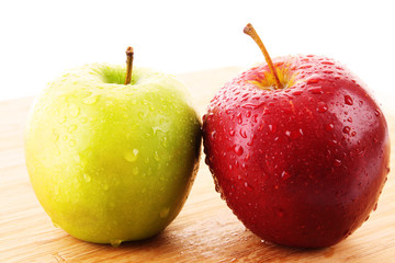 Red apple and green on wooden surface with water drops