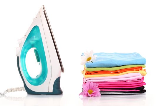 Pile of colorful clothes and electric iron  over white backgroun