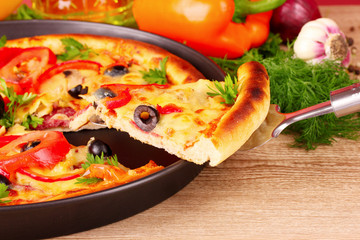 pizza and vegetables on wooden background