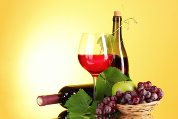 Red wine and fruits on yellow background