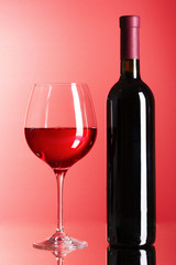 Wine bottle and glass on red background
