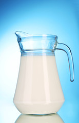 Pitcher with milk on blue background