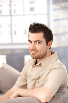 Portrait of young man sitting on sofa smiling