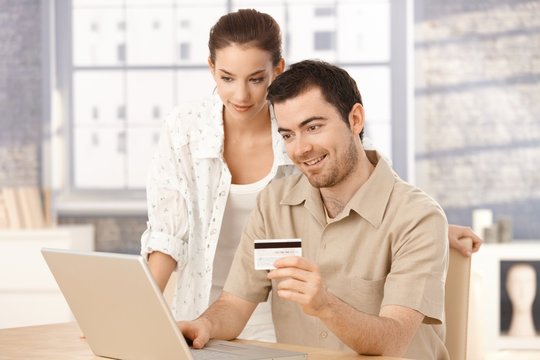 Happy couple shopping online at home smiling