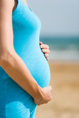 Fototapeta na wymiar woman is holding pregnant belly on the beach