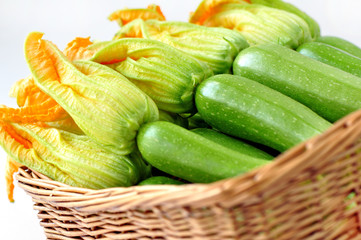 Zucchini with flowers in a basket on a white background