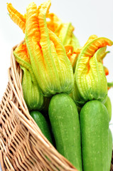 Zucchini with flowers in a basket on a white background