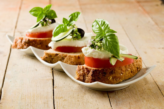 Tartine di pomodoro e mozzarella su letto di pane ai cereali