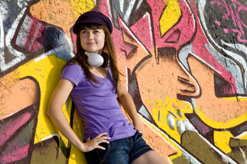 Obraz na płótnie Canvas Beautiful brunette girl with headphones and graffiti wall at bac