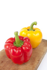 yellow and red, yellow and red bell peppers on a wood plate.