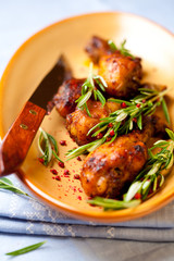 Roasted chicken legs with rosemary sprigs and pink pepper