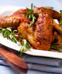 Roasted chicken wings with rosemary sprigs and pink pepper