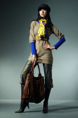 Attractive young fashion model in hat with hand bag