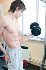 Fototapeta na wymiar Powerful muscular man lifting weights in gym