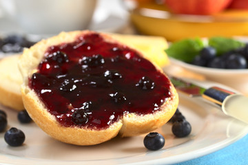 Blueberry jam on half a bun with fresh blueberries