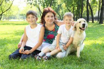Mother and her two sons in the park with a dog