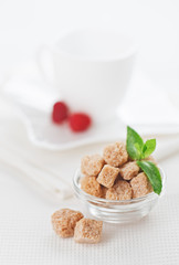 Still life with brown lump cane sugar, on white linen table clot