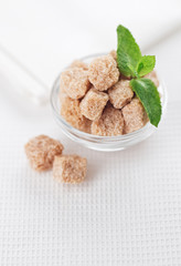 Still life with brown lump cane sugar, on white linen table clot