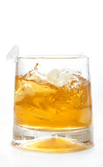 glass of whiskey with ice cubes splashing out over white