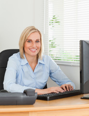 Working blonde woman in front of a screen looks into camera