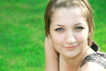 Beautiful smiling girl with blue eyes on green grass background