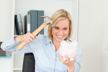 Smiling blonde woman wanting to destroy her piggy bank