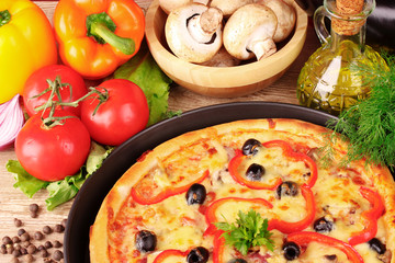 tasty pizza with olives and vegetables on a wooden background