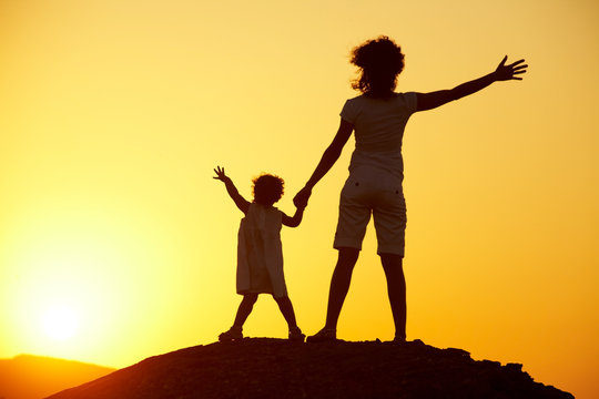 Silhouette of  young woman with  child against the bright sunset