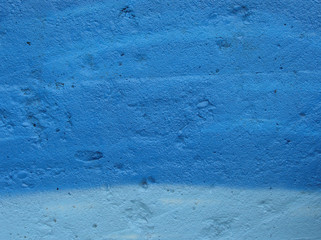 concrete wall spray painted in 2 types of blue