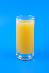 Orange juice in glass on blue background