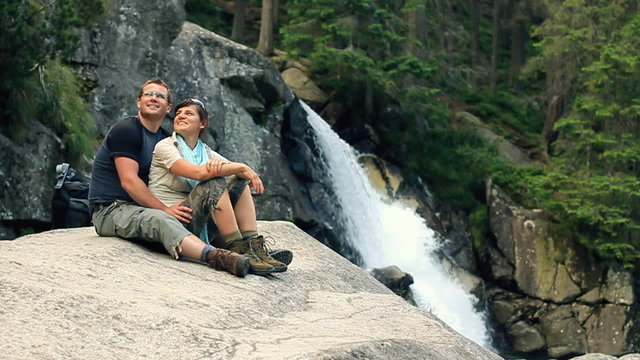 Happy couple relaxing by the beautiful waterfall, slow motion