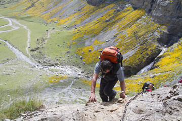 Hombre cruzando un paso complicado en una senda de montaña