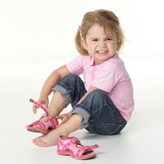 Adorable little girl is annoyed to put on her shoes