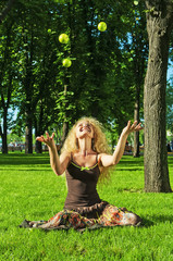 Portrait of young laughing girl throwing up green apples