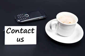 Contact us noted on desk with coffee