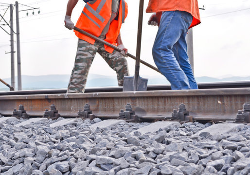 railway embankment, rails and workers in orange vests