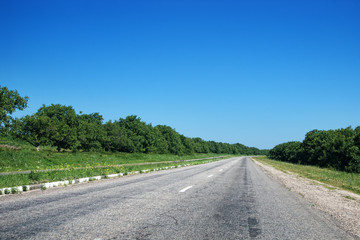 Empty old countryside highway road with trees and blue sky