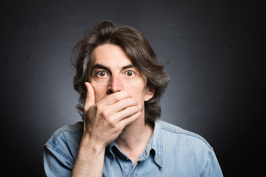 Scared Adult Man With Hand Covering Mouth And Dramatic Lighting