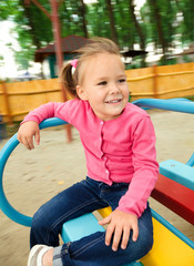 Fototapeta na wymiar Cute little girl is riding on merry-go-round