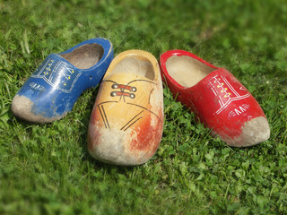Fototapeta premium Three colored old wooden shoes on grass
