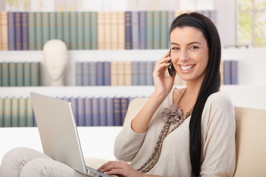 Laughing woman with laptop on call