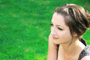 Beautiful girl looking at on green grass background on sunny day