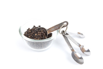 measure pepper, black pepper in a cup with table spoon inside.