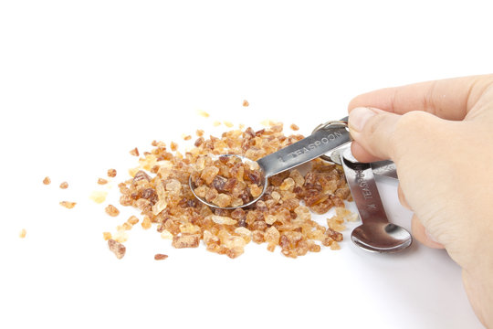 female hand use silver tablespoon measuring rock sugar.